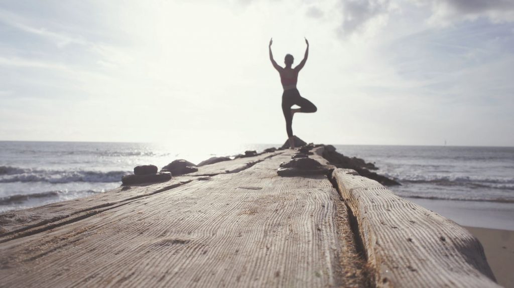 Woman doing yoga post on cliff